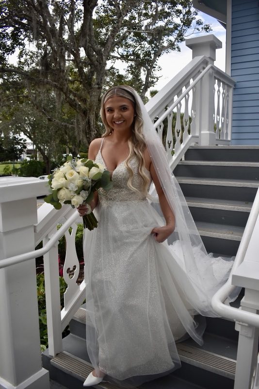 Bride with her bouquet showing off her finished wedding gown outdoors