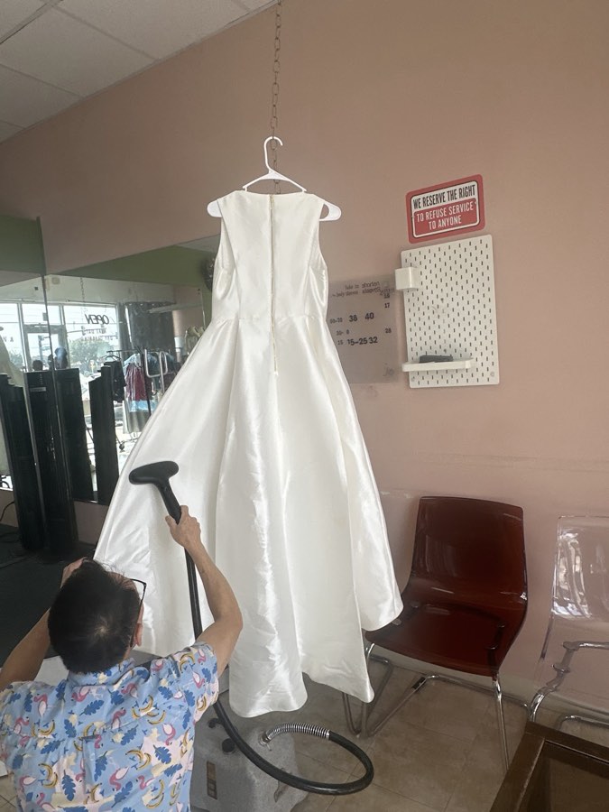 A finished white dress being steamed before pickup