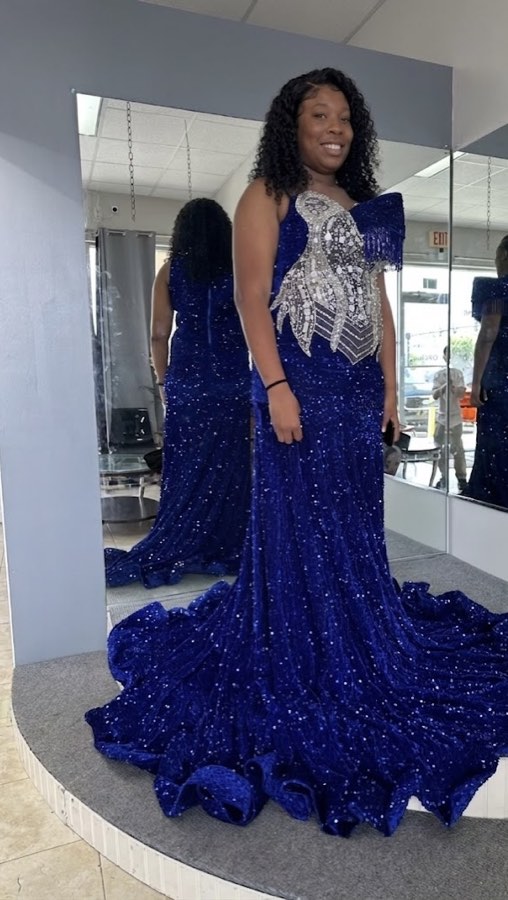 Client in a royal blue sequined gown with a long train on the fitting platform